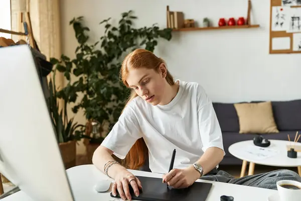 Un joven se centra en la elaboración de ilustraciones digitales en su escritorio moderno rodeado de plantas. - foto de stock