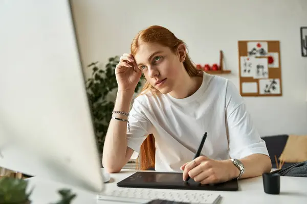 A young man thoughtfully illustrates on a tablet in a bright, contemporary office setting. — Stock Photo