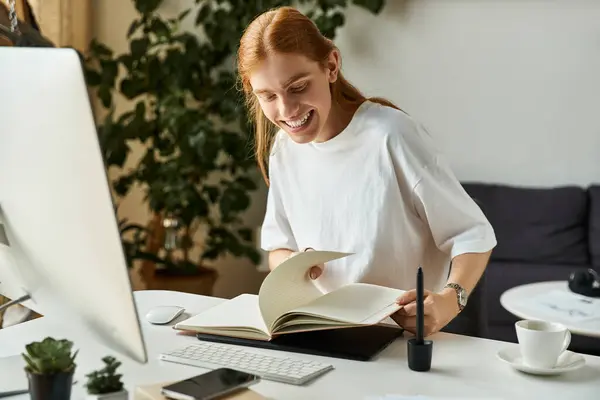 A young man smiles while enjoying a book in his bright and creative workspace. — Stock Photo