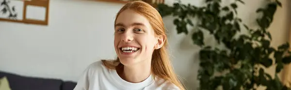 A cheerful young man with red hair enjoys a moment of happiness in a warm, inviting space. — Stock Photo