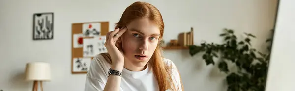 Der junge Mann sitzt an seinem Schreibtisch, tief beschäftigt mit der Arbeit, umgeben von Pflanzen und kreativem Dekor.. — Stockfoto