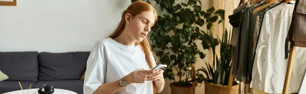 A young man focuses on a mobile device while surrounded by trendy decor and plants. — Stock Photo