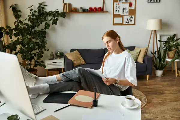 A young man sits back with his feet on a table, thoughtfully examining papers in a stylish home. — Stock Photo