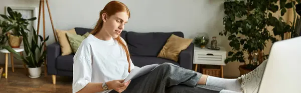 A young man sits comfortably on a sofa, deeply focused on his reading material while relaxing. — Stock Photo