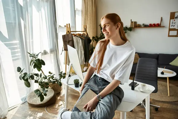 A young man sits comfortably in a bright room, surrounded by greenery and soft furnishings. — Stock Photo
