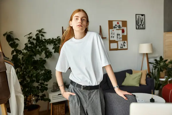 A young man stands confidently in a modern, well decorated room showcasing casual fashion. — Stock Photo