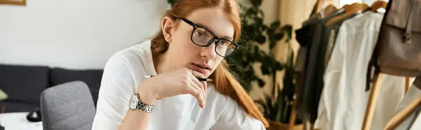 A young man with glasses ponders thoughtfully while seated in a stylish, bright room. — Stock Photo