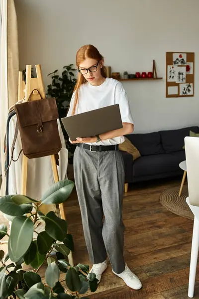 The young man stands focused, using a laptop in a stylish and warm interior. — Stock Photo