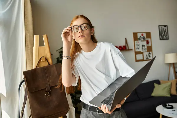 A young man in glasses looks up from his laptop, deep in thought in a cozy setting. — Stock Photo