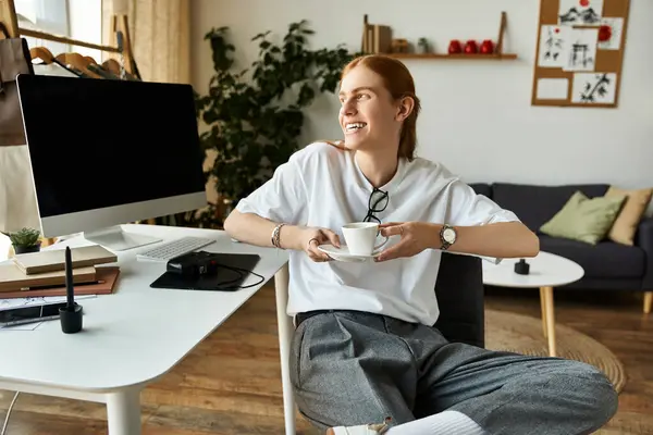 A cheerful young man savors a cup of tea in his stylish workspace, embracing comfort and creativity. — Stock Photo