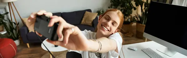 Молодой человек ярко улыбается, делая селфи в стильном, привлекательном жилом помещении. — стоковое фото