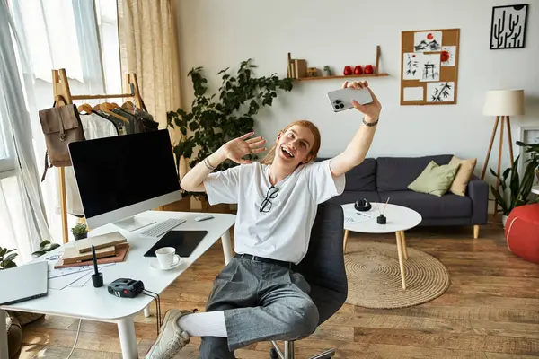 The young man smiles and waves while capturing a selfie in his vibrant workspace. — Stock Photo