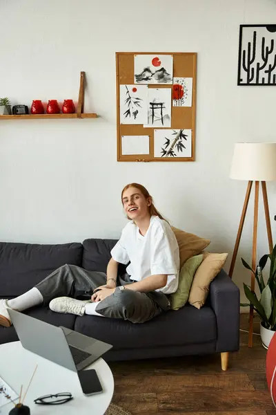 Um jovem sorri enquanto se senta confortavelmente em um sofá em um quarto lindamente decorado. — Fotografia de Stock