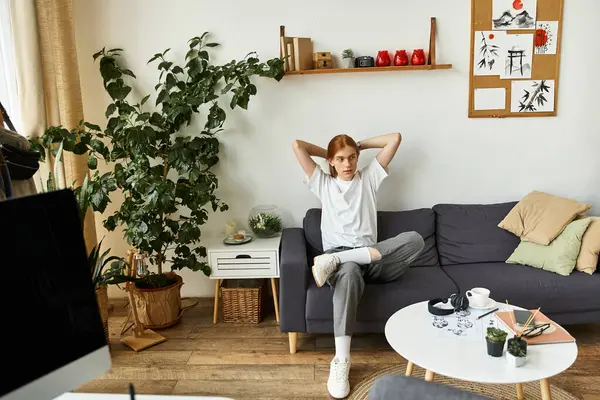 A relaxed young man sits comfortably on a couch, enjoying his tranquil living space. — Stock Photo