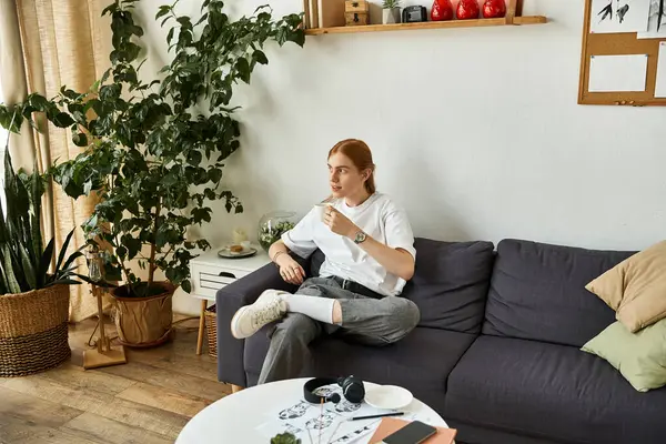 A young man enjoys a moment of tranquility in a stylish room filled with greenery. — Stock Photo