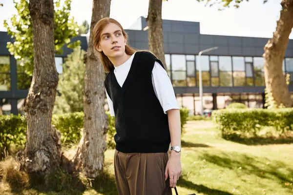 A young man with a thoughtful expression enjoys a stroll in a serene park setting. — Stock Photo