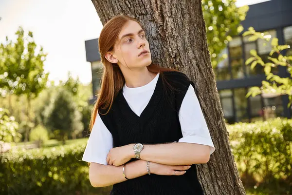A young man reflects near a tree surrounded by greenery on a sunny afternoon. — Stock Photo