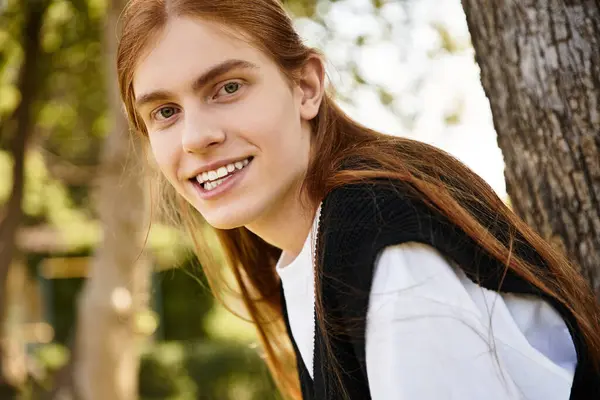 A cheerful young man enjoys a sunny day outdoors, chatting and engaging with nature. — Stock Photo