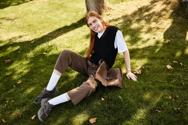 This young man smiles brightly, lounging comfortably on the grass in a sunny park setting. — Stock Photo