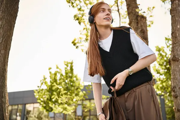 A young man with headphones smiles while embracing nature on a bright day. — Stock Photo