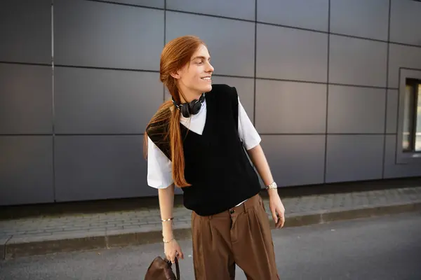 Un joven vestido casualmente disfruta de un momento con una sonrisa alegre en un entorno moderno de la ciudad. - foto de stock