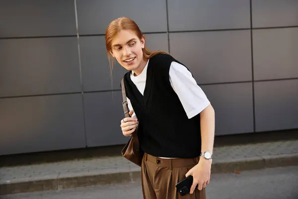 The young man is smiling and looking toward the camera while walking down the street. — Stock Photo