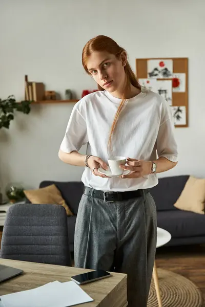 A young man stands relaxed, holding a cup, in a stylish, inviting home environment. — Stock Photo