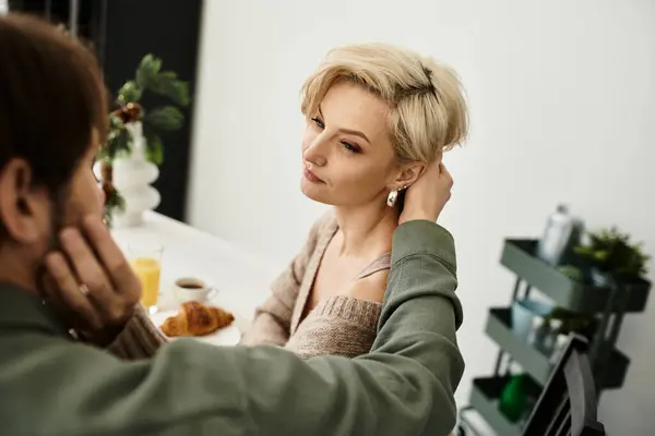 A couple enjoys a quiet breakfast as they express affection in their intimate home setting. — Stock Photo