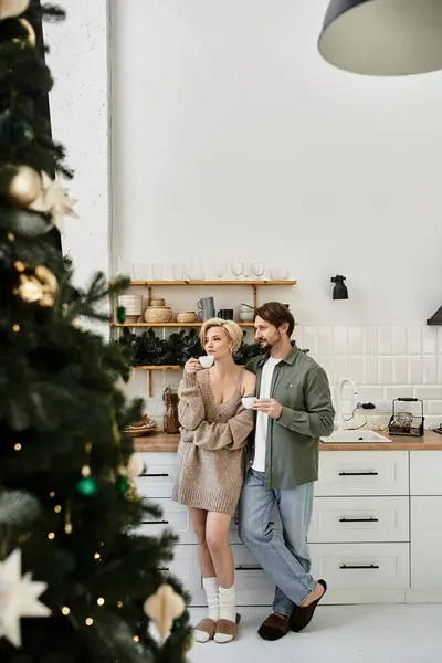 A man and woman share a warm moment in their kitchen, sipping tea and smiling together. — Stock Photo