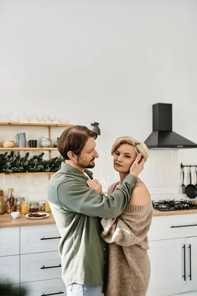 A couple enjoys a tender moment in their modern kitchen while embracing each other affectionately. — Stock Photo