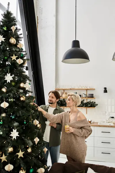 In a cozy home, a happy couple lovingly adorns their Christmas tree amidst warm decorations. — Stock Photo