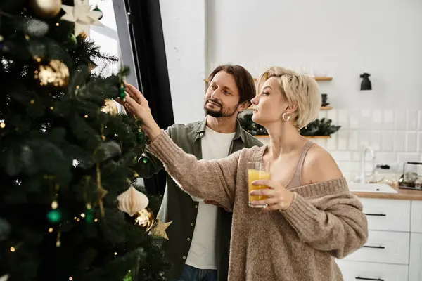 A couple joyfully decorates their Christmas tree, embracing holiday spirit together. — Stock Photo
