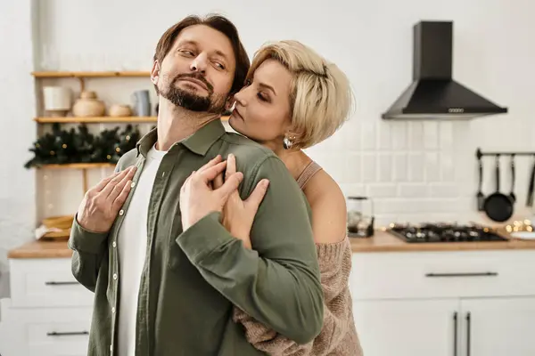 The couple shares a warm embrace in their inviting kitchen, radiating affection and joy. — Stock Photo