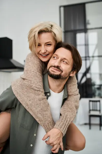 A loving couple shares a warm embrace, laughing and enjoying a carefree moment in their home. — Stock Photo