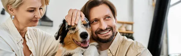 A loving couple enjoys quality time at home while playing with their cheerful dog. — Stock Photo