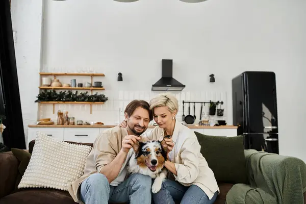 A joyful couple pets their dog while sharing a tender moment at home together. — Stock Photo