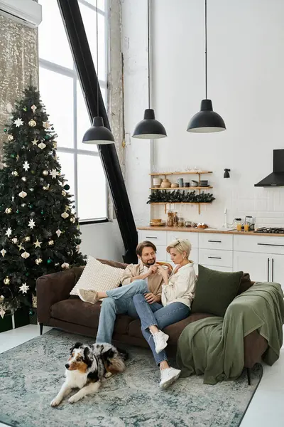 Um casal compartilha momentos doces em um sofá em sua casa elegante, cercado por decorações de férias. — Fotografia de Stock