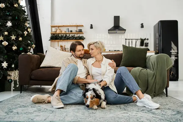 A couple enjoys a relaxed evening together, surrounded by holiday decorations and their pet dog. — Stock Photo