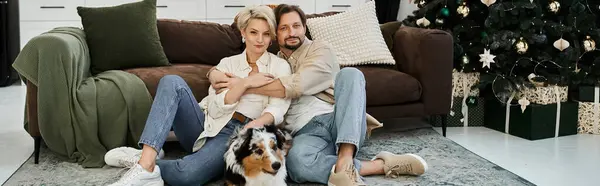 A couple embraces each other while sitting on a rug, sharing warmth with their pet dog nearby. — Stock Photo