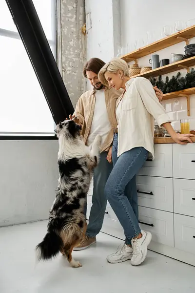 Ein Paar teilt einen zärtlichen Moment mit seinem verspielten Hund in einem warmen, einladenden Küchenraum. — Stockfoto