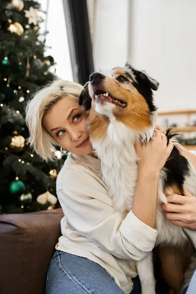 A woman cuddles with her dog in a festive, cozy living room. — Stock Photo