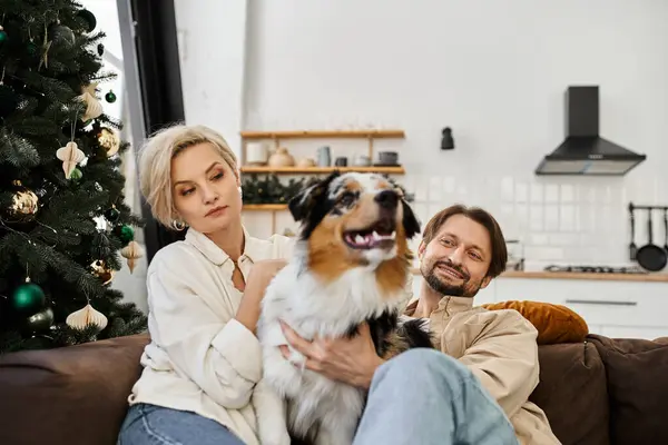 Un couple se détend ensemble sur un canapé avec leur chien, embrassant la chaleur de la maison. — Photo de stock