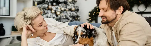 A couple enjoys a tender moment with their dog while cozying up at home during the holidays. — Stock Photo