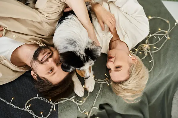 A couple enjoys quality time together while snuggling with their dog on a soft blanket at home. — Stock Photo