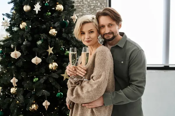 A loving couple holds glasses of sparkling beverage while enjoying a cozy moment at home. — Stock Photo