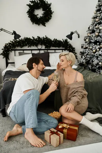 Un couple partage un moment tendre à la maison, entouré de décorations et de cadeaux de vacances. — Photo de stock