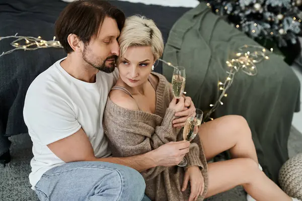 A couple enjoys a cozy moment at home, sharing drinks and warmth amidst soft lights. — Stock Photo