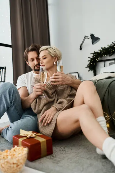 A couple in a warm embrace enjoys festive drinks together in a cozy living space. — Stock Photo