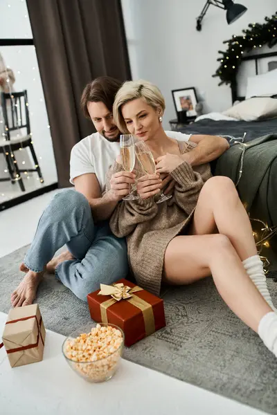 Un couple se détend sur le sol à la maison, sirotant des boissons et célébrant leur temps ensemble. — Photo de stock