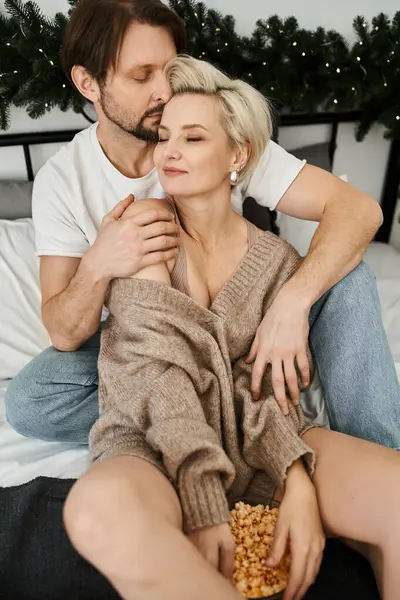 A couple sits together in a cozy bedroom, sharing intimate laughter and popcorn. — Stock Photo